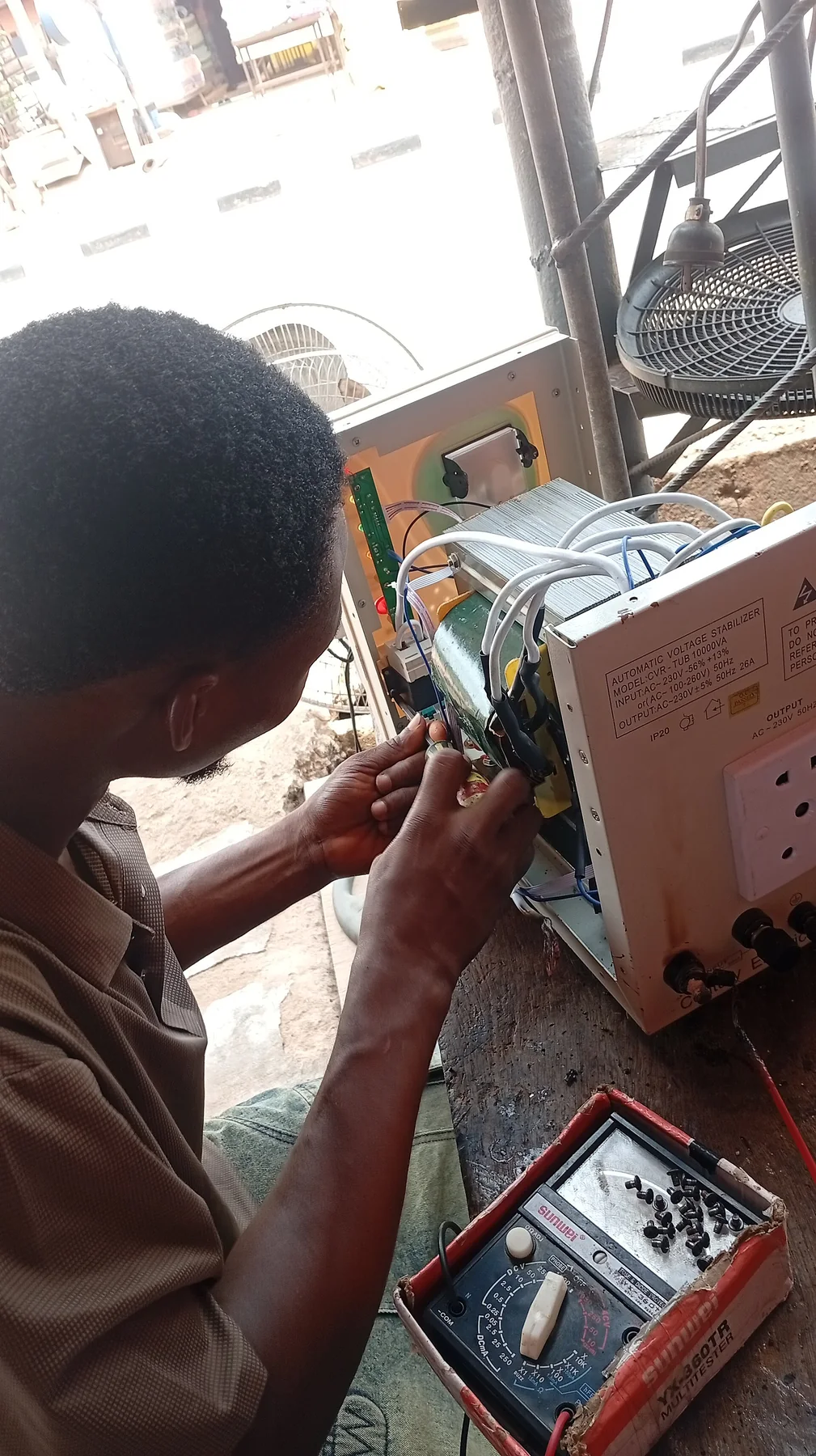 A technician works on electronic equipment at a repair bench.