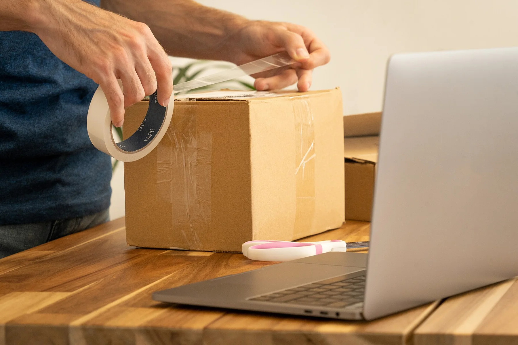A parcel is sealed beside a laptop used to arrange shipping.