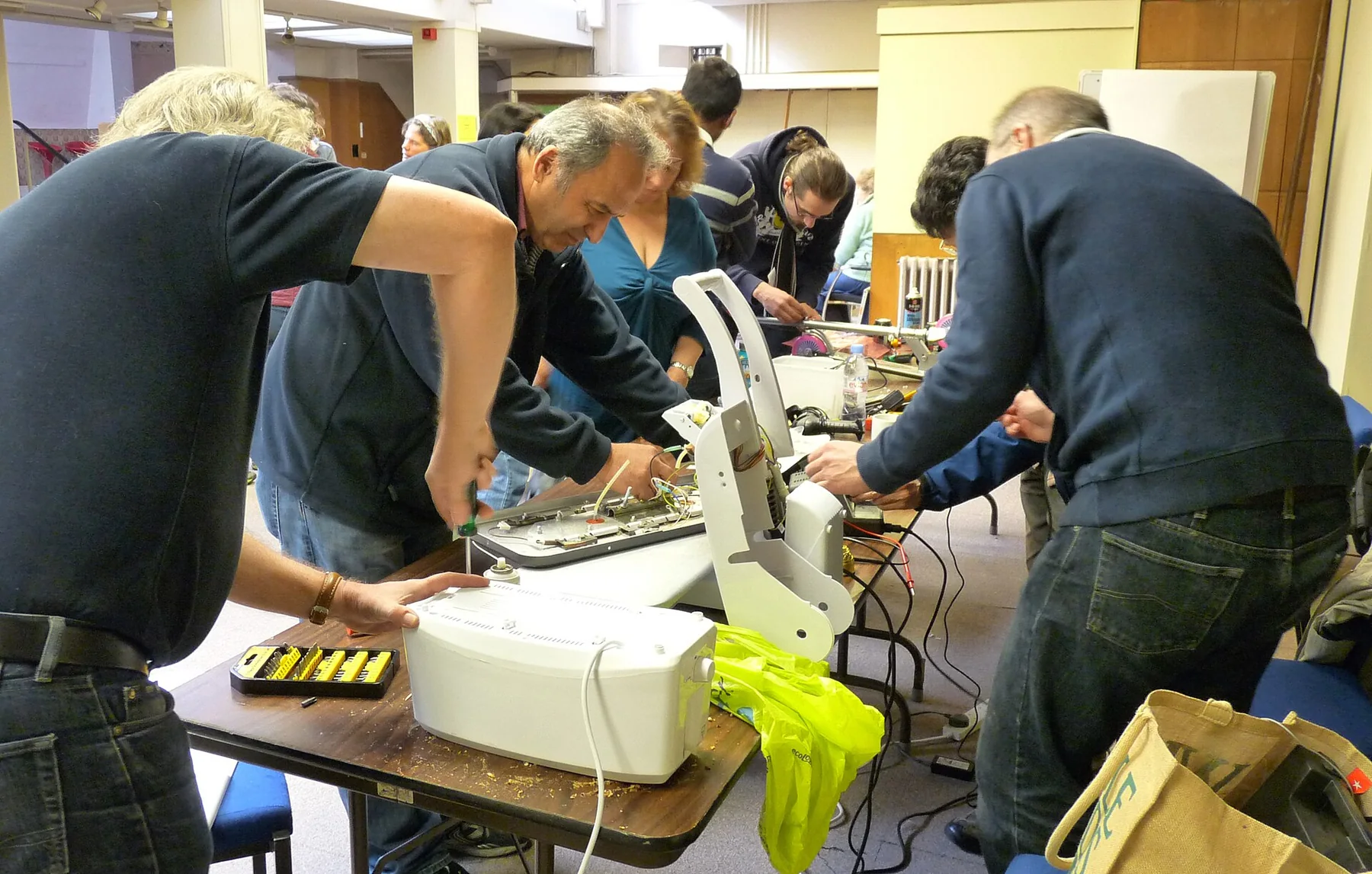 Volunteers and visitors work together at a community repair workshop.