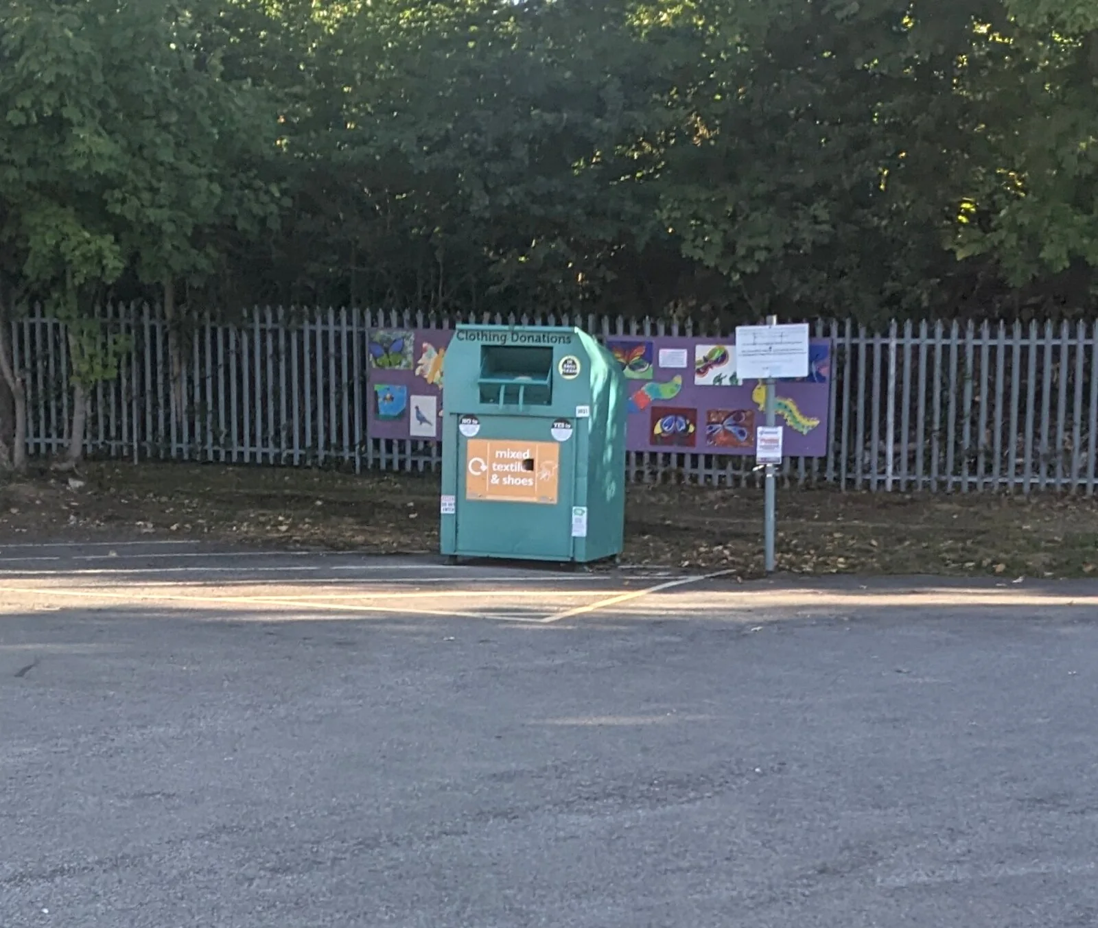 A clothing donation bin stands at a public collection point.